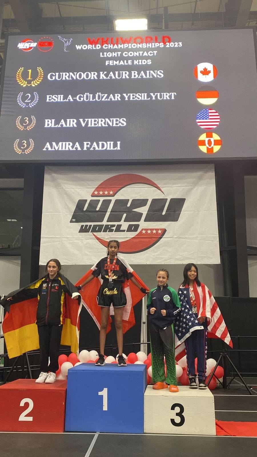 DMA Academy athlete Gurnoor Kaur Bains standing atop the #1 podium as WKU World Championships 2023 Light Contact champion for Canada