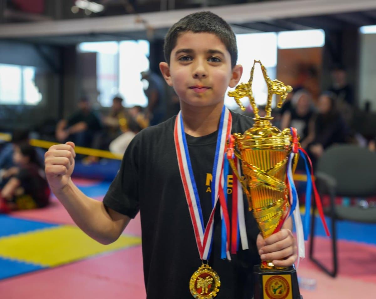 Young DMA student holding a championship trophy and medal